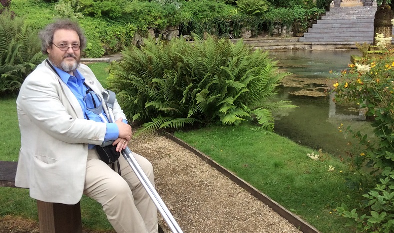 Person sits in landscaped garden whislt holding crutches 