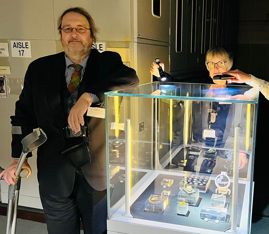 Two people stand next to glass display case