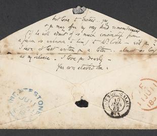 An envelope with the lines of text written on the flap and postmarks on the front